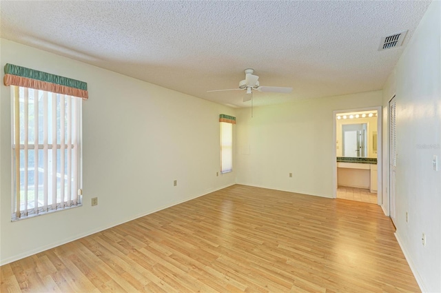 empty room with visible vents, a ceiling fan, a healthy amount of sunlight, and light wood-type flooring