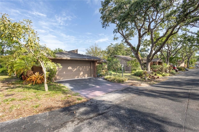 view of side of property featuring aphalt driveway and a garage