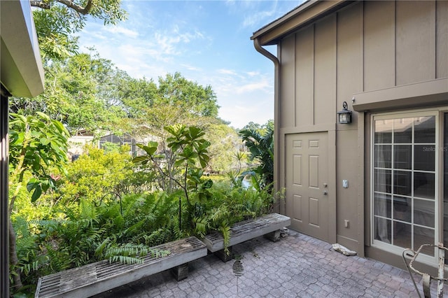 view of exterior entry with board and batten siding and a patio