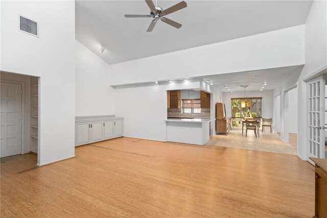unfurnished living room featuring ceiling fan, light wood-style floors, visible vents, and high vaulted ceiling