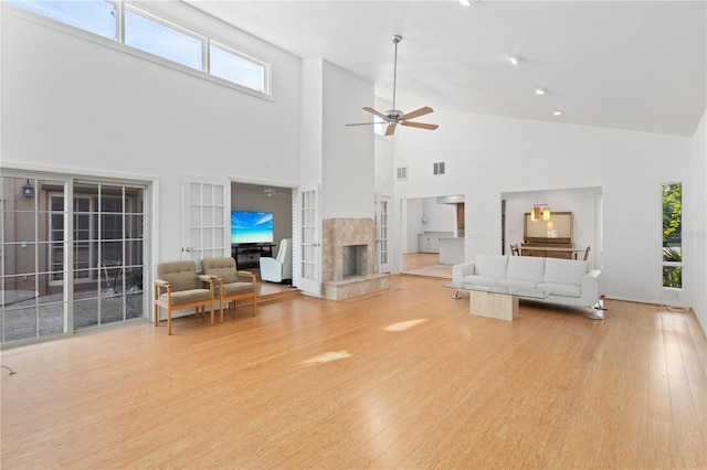 living room featuring wood finished floors, a ceiling fan, a premium fireplace, and high vaulted ceiling
