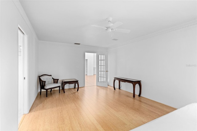 living area featuring ornamental molding, light wood-type flooring, a ceiling fan, and visible vents