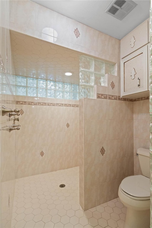 full bath with tile walls, toilet, visible vents, a walk in shower, and tile patterned flooring
