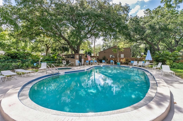 community pool with a patio and fence