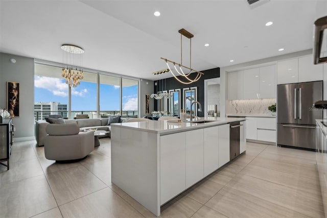 kitchen with appliances with stainless steel finishes, a sink, modern cabinets, white cabinetry, and a chandelier