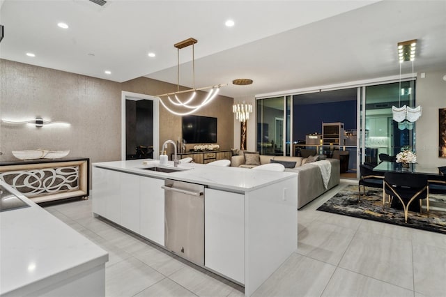 kitchen featuring stainless steel dishwasher, white cabinetry, a sink, open floor plan, and pendant lighting
