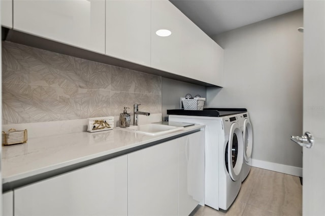 laundry room with separate washer and dryer, cabinet space, and baseboards