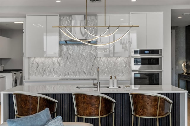 kitchen with stainless steel double oven, separate washer and dryer, modern cabinets, white cabinets, and recessed lighting