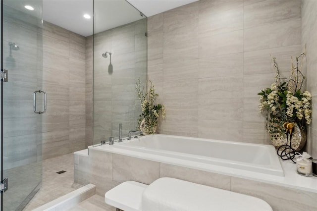 bathroom with a stall shower, a garden tub, tile walls, and toilet