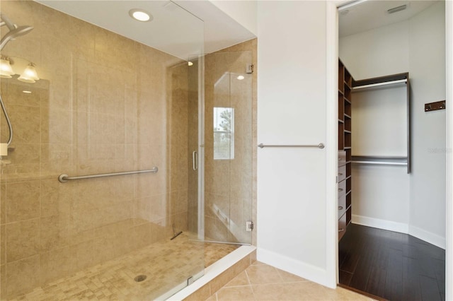 full bath with a shower stall, a spacious closet, and baseboards