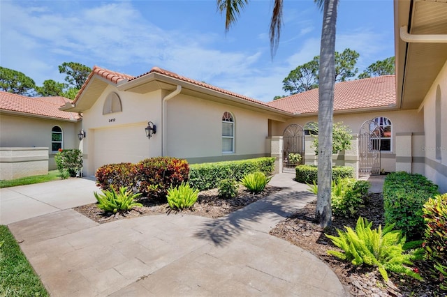 view of side of home with a tiled roof, an attached garage, driveway, and stucco siding