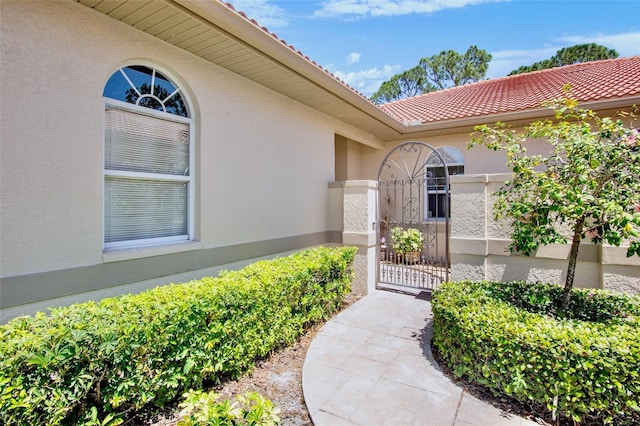 property entrance featuring a gate, stucco siding, and a tiled roof