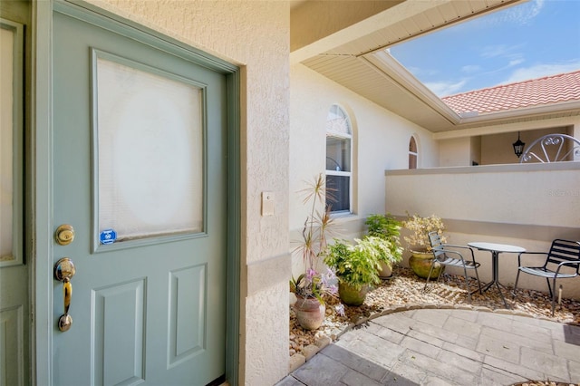 property entrance with fence, stucco siding, and a patio area
