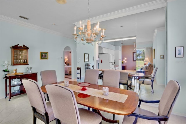 dining room featuring visible vents, crown molding, arched walkways, baseboards, and a notable chandelier