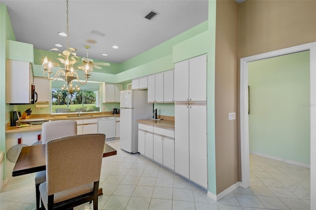 kitchen featuring a notable chandelier, a sink, white appliances, light countertops, and visible vents