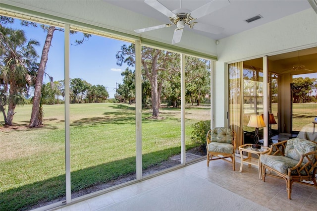 sunroom with a healthy amount of sunlight, a ceiling fan, and visible vents