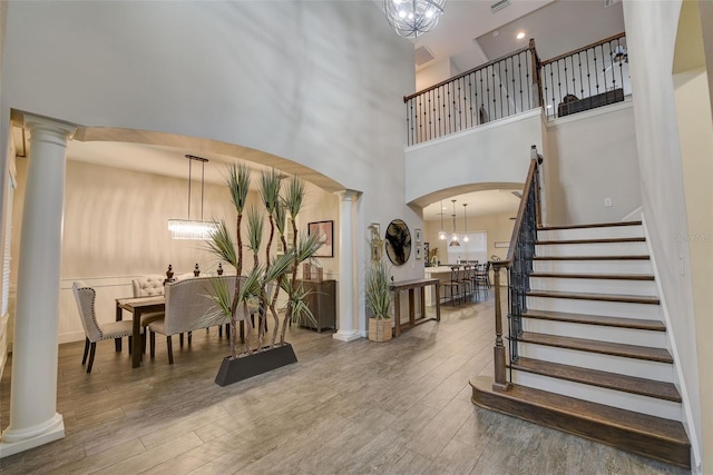 6001 Anise Dr, Sarasota, FL 34238 - entryway with a towering ceiling, wood finished floors, stairway, ornate columns, and a notable chandelier