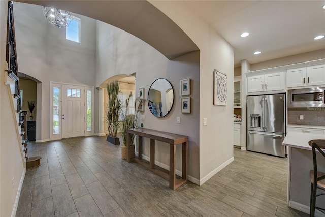 6001 Anise Dr, Sarasota, FL 34238 - foyer entrance featuring arched walkways, baseboards, plenty of natural light, and light wood finished floors