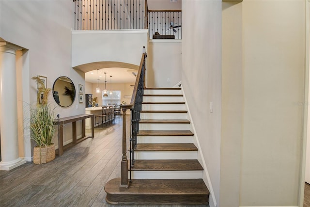 6001 Anise Dr, Sarasota, FL 34238 - stairway with baseboards, arched walkways, a towering ceiling, and wood finished floors
