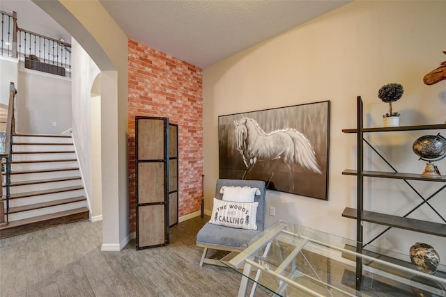 6001 Anise Dr, Sarasota, FL 34238 - sitting room featuring arched walkways, baseboards, wood finished floors, and stairway