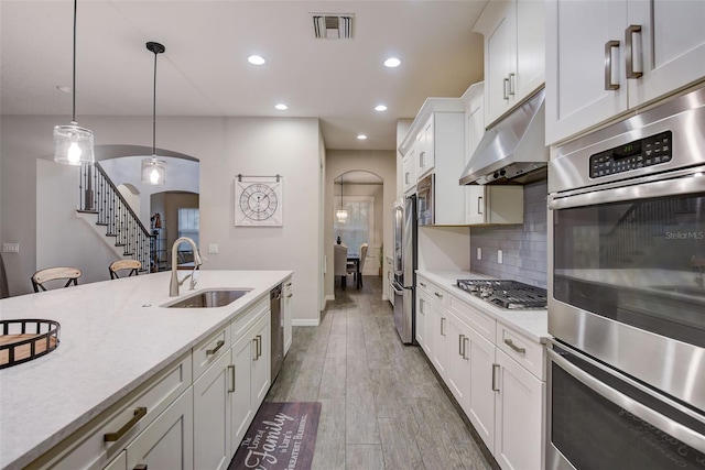 6001 Anise Dr, Sarasota, FL 34238 - kitchen with a sink, arched walkways, white cabinetry, stainless steel appliances, and under cabinet range hood