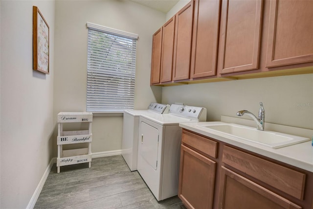 6001 Anise Dr, Sarasota, FL 34238 - laundry area featuring cabinet space, a sink, light wood-style floors, baseboards, and washer and clothes dryer