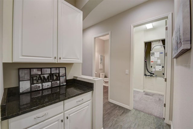 6001 Anise Dr, Sarasota, FL 34238 - interior space featuring white cabinets, baseboards, dark stone counters, and light wood finished floors
