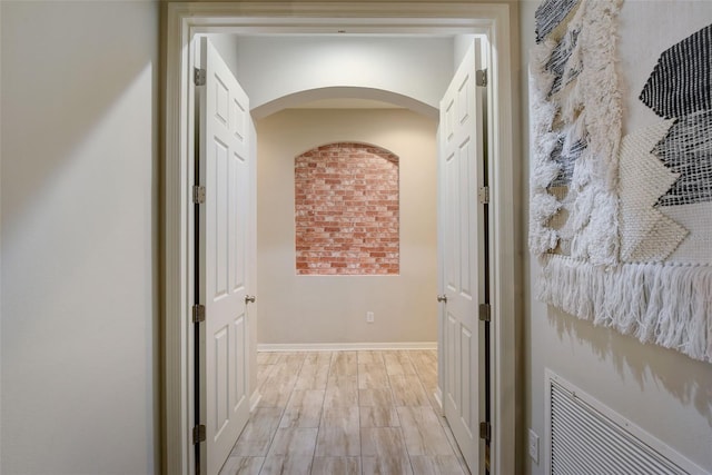 6001 Anise Dr, Sarasota, FL 34238 - hallway featuring baseboards, arched walkways, light wood-style flooring, and visible vents
