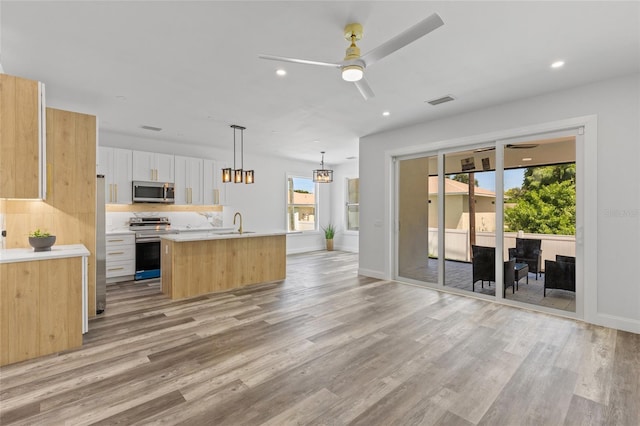 532 Yale Rd, Venice, FL 34293 - kitchen with light wood-style floors, a kitchen island with sink, light countertops, stainless steel appliances, and a ceiling fan