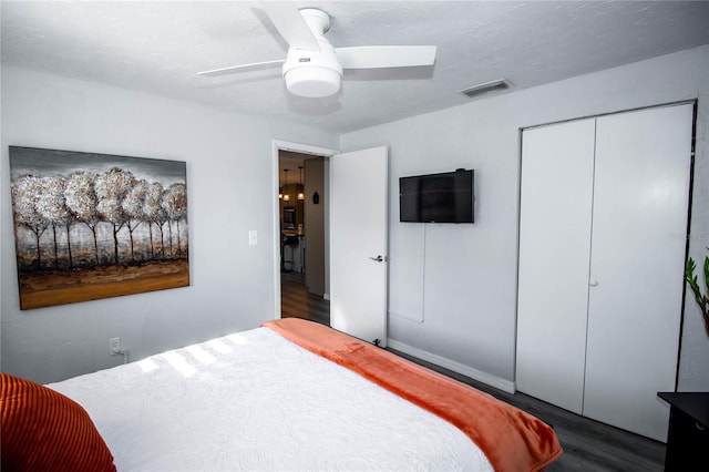 bedroom with ceiling fan, a closet, wood finished floors, and visible vents