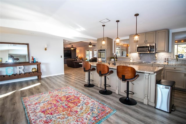 kitchen featuring a breakfast bar, stainless steel appliances, wood finished floors, and open floor plan