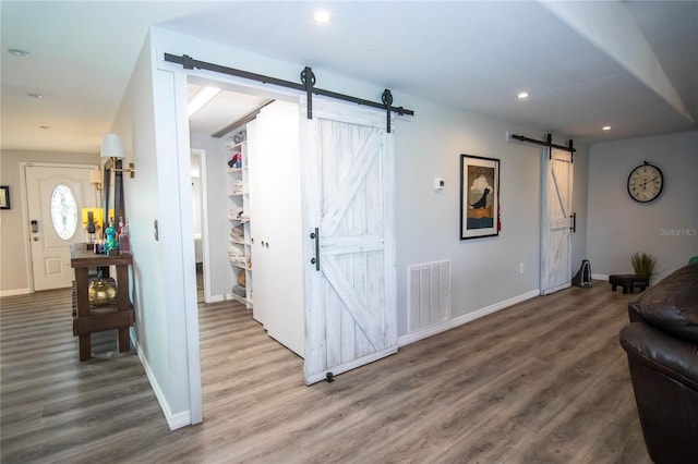 living area with wood finished floors, baseboards, a barn door, and visible vents