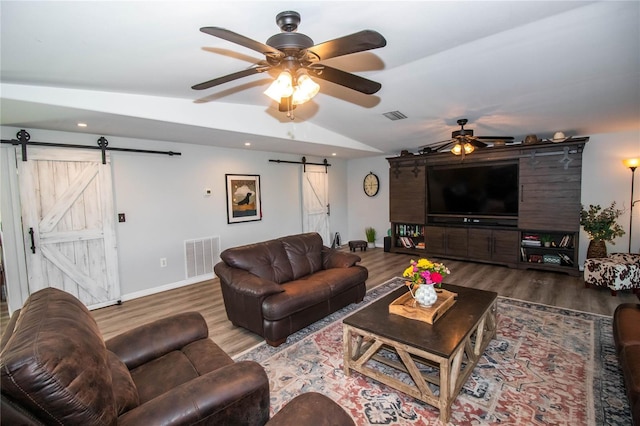 living area featuring visible vents, wood finished floors, a barn door, a ceiling fan, and vaulted ceiling
