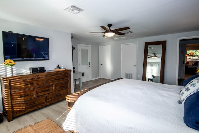 bedroom with visible vents, a ceiling fan, multiple closets, and wood finished floors
