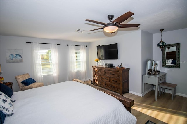 bedroom with baseboards, ceiling fan, wood finished floors, and visible vents