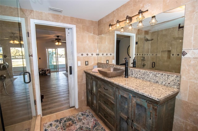 bathroom featuring visible vents, tile patterned flooring, vanity, tile walls, and a stall shower