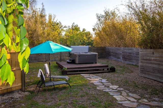 view of yard featuring a hot tub, a deck, and a fenced backyard