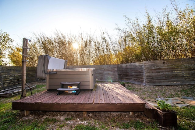 wooden deck with a hot tub and a fenced backyard