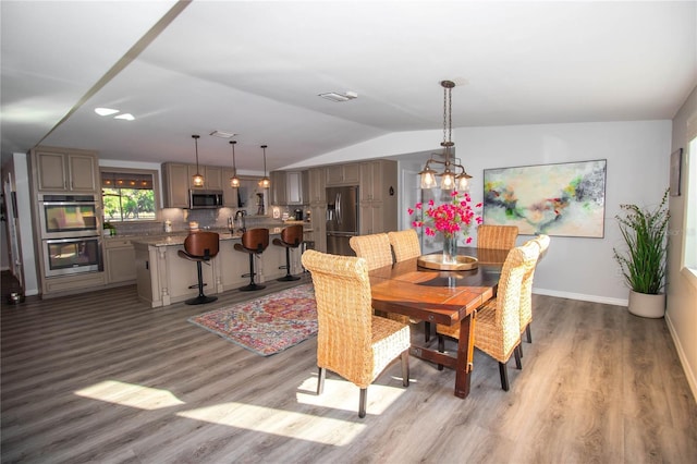 dining room with a notable chandelier, baseboards, vaulted ceiling, and wood finished floors