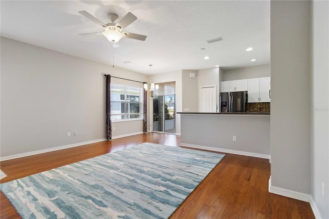 unfurnished living room featuring baseboards, dark wood-style floors, and ceiling fan with notable chandelier