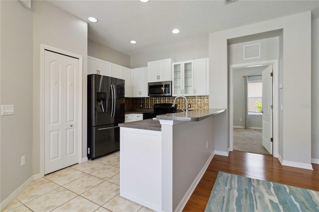 kitchen featuring decorative backsplash, a peninsula, glass insert cabinets, white cabinets, and black appliances