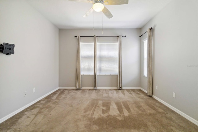 carpeted empty room featuring baseboards and ceiling fan