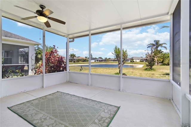 unfurnished sunroom with a ceiling fan, a healthy amount of sunlight, and a water view