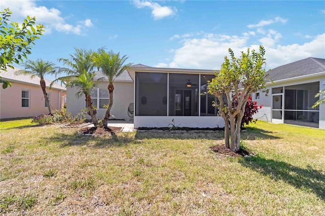 rear view of house with a lawn, stucco siding, and a sunroom