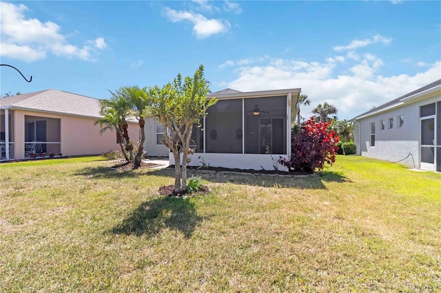 rear view of property featuring a sunroom, stucco siding, and a yard
