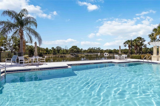 pool featuring a patio, a water view, and fence
