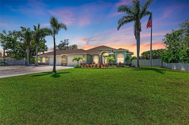 view of front of house with driveway, a garage, fence, a yard, and stucco siding