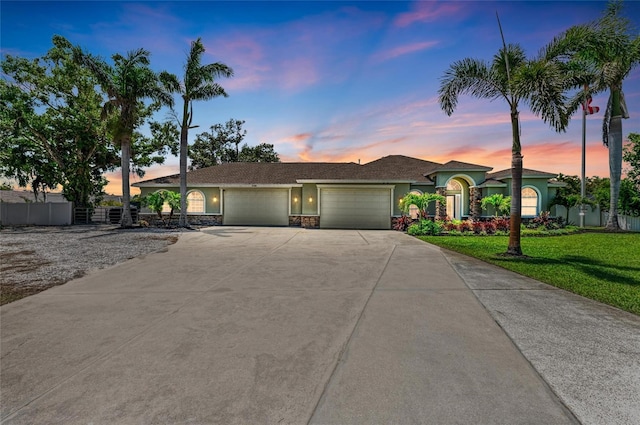 view of front of home featuring fence, driveway, stucco siding, an attached garage, and a yard