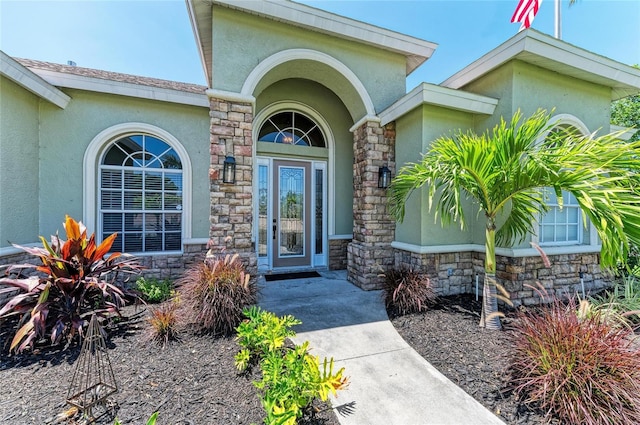 view of exterior entry featuring stucco siding and stone siding