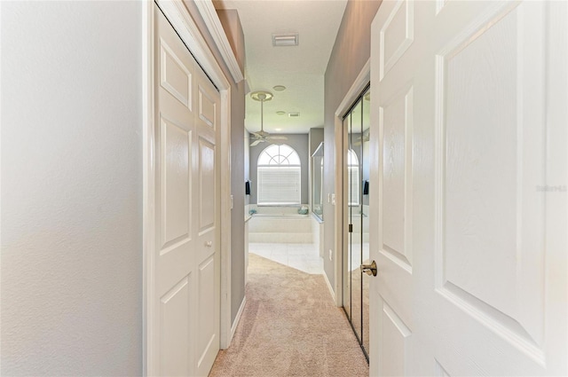 hallway featuring light carpet and visible vents